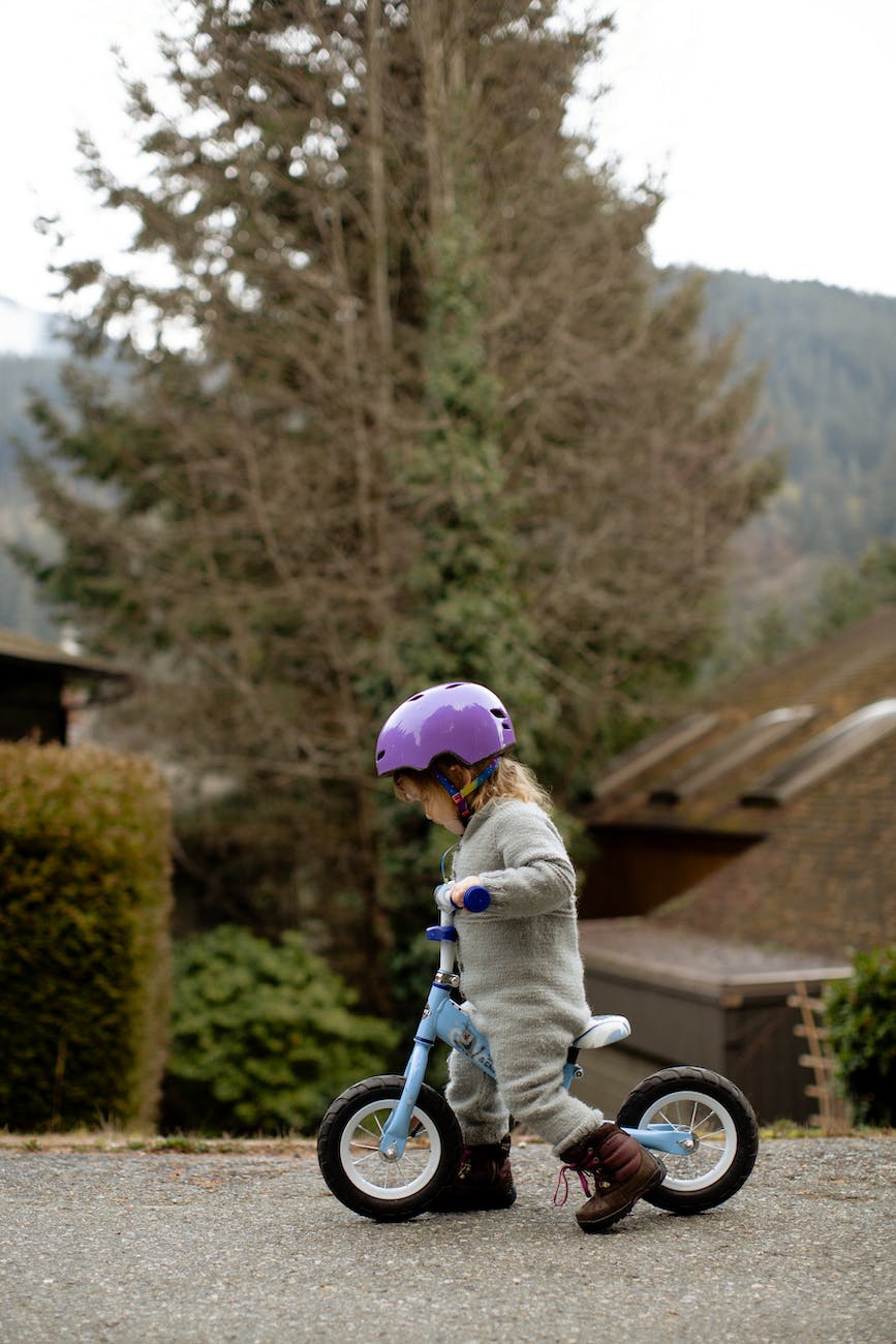 little girl in helmet riding run bike on street in countryside